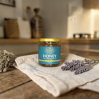 Jar of honey with a blue label on a wooden surface with lavender flowers