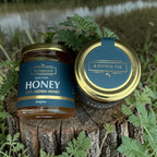 Two jars of Heather Honey by The Natural B on a wooden surface with a natural background